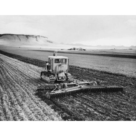 Tractor pulling a harrow in a wheat field Poster Print
