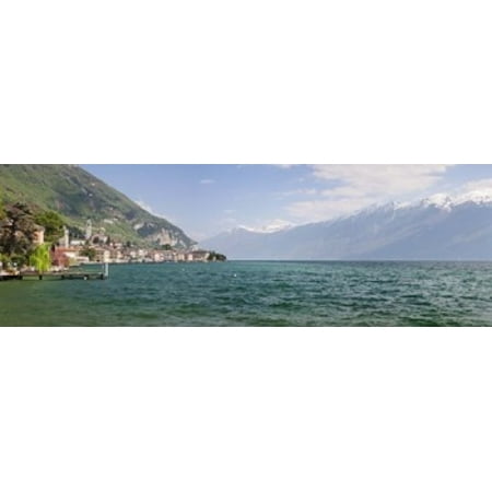 Buildings at the waterfront with snowcapped mountain in the background Gargnano Monte Baldo Lake Garda Lombardy Italy Stretched Canvas - Panoramic Images (18 x 6)