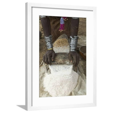 Africa, Ethiopia, Southern Omo, Karo Tribe. Woman grinding grain into flour with stone. Framed Print Wall Art By Ellen Goff