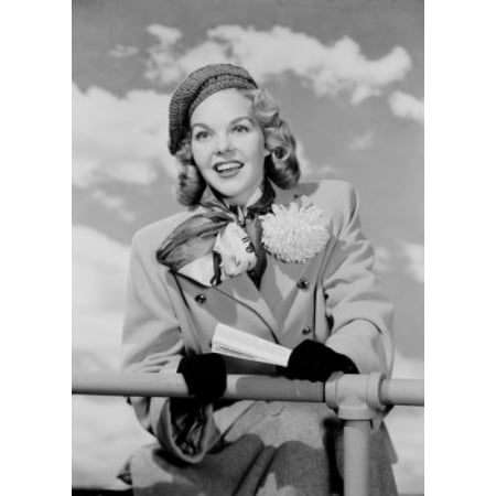 Young woman in coat leaning on fence Poster Print