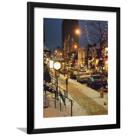 Snow Covered City Street with Decorative Christmas Lights in Trees at Night Framed Print Wall Art