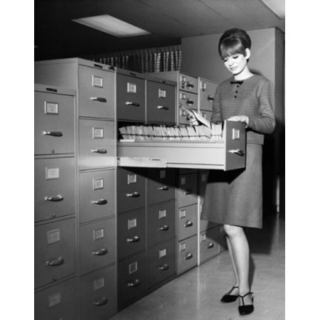 Businesswoman searching for files in a filing cabinet Poster Print