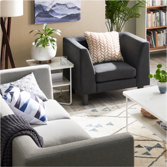 A modern living room decorated in the Scandinavian minimal style by MoDRN with a modular arm chair, modular sofa and geometric area rug.