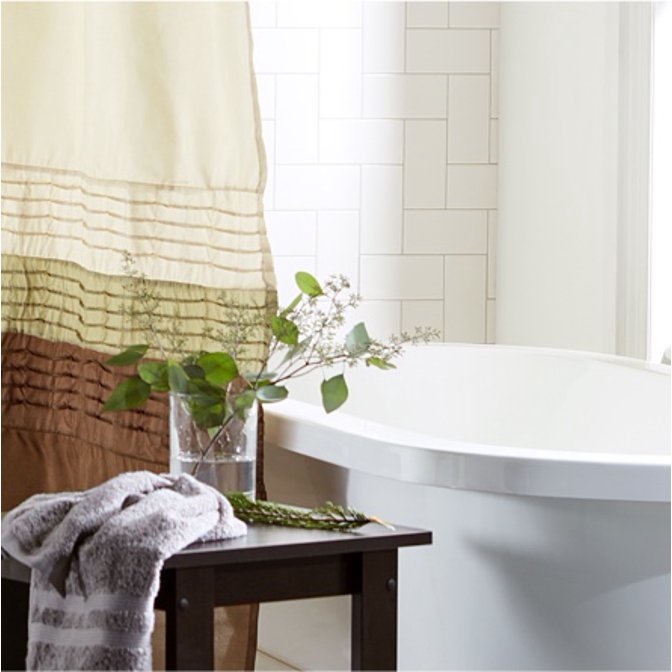 A master bathroom decorated in the traditional style with a brown shower curtain, bath tub, and a house plant on a wooden stool.