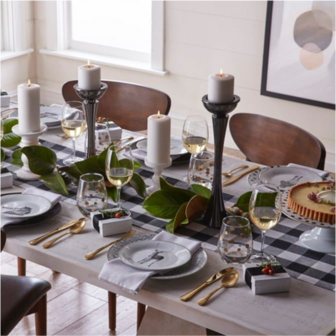 A table setting with Danish modern dining chairs, a checkered table runner, gold glassware and stylish holiday decor.