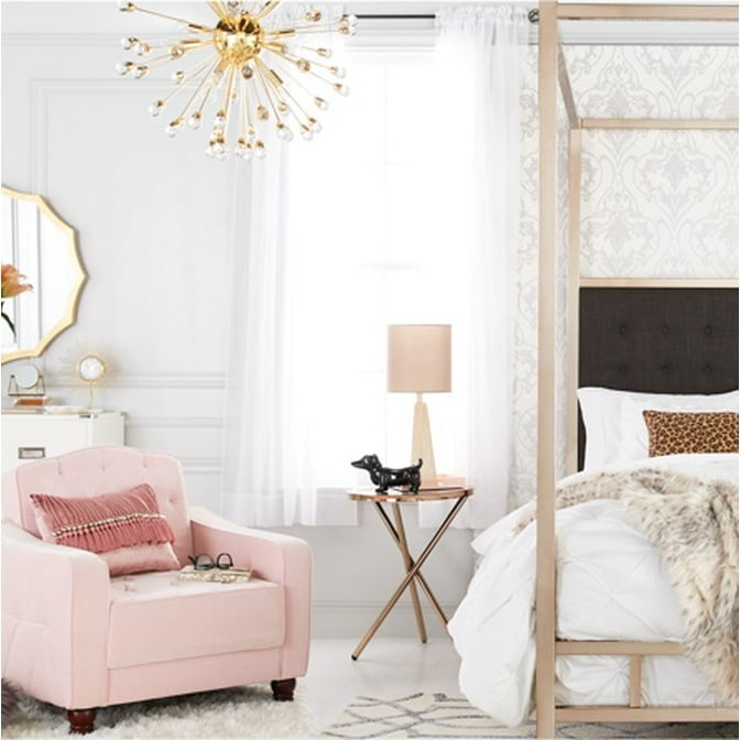 A romantic bedroom with a pink armchair and a champagne four-poster canopy bed and a gold sputnik chandelier.