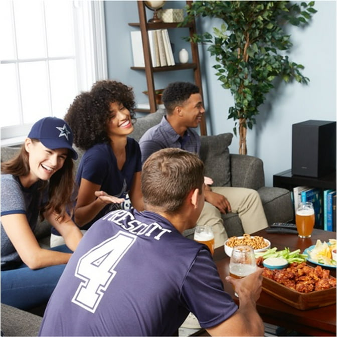 A group of friends sitting on a gray sectional, eating snacks and getting ready to watch the football game