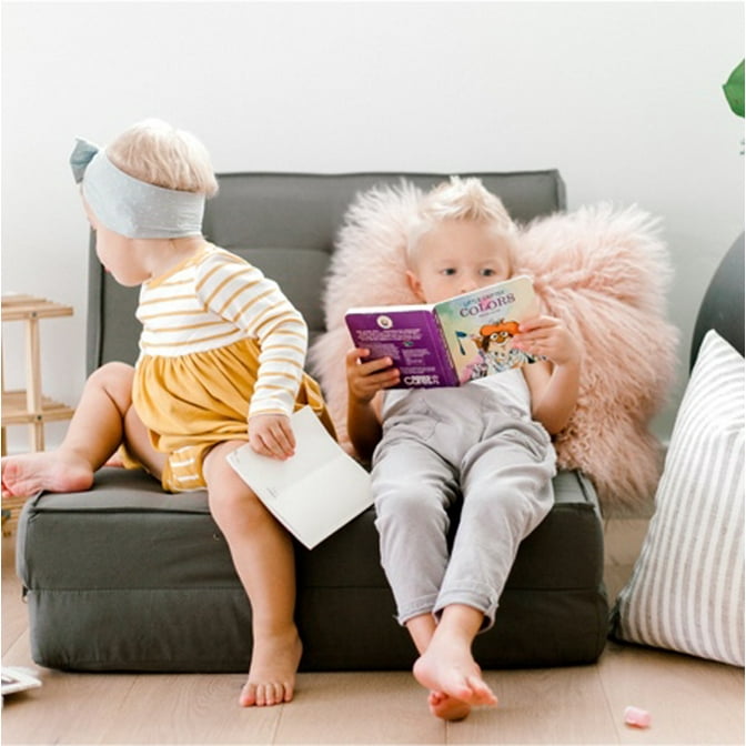 Two toddlers sitting on a Your Zone flip chair with a faux fur pillow and a shoe shelf bookshelf.