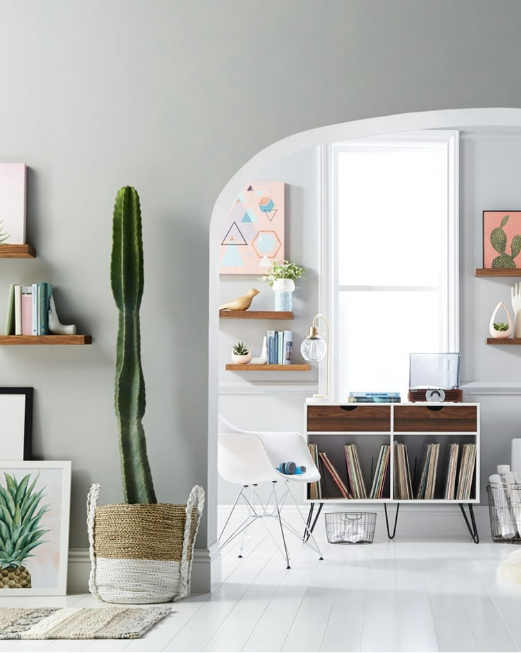 A picture of a bedroom as seen through an archway with a stylish sideboard being used to store vinyl record albums and more as well as wooden wall shelves showcasing artwork.