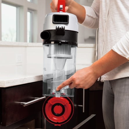 A woman opening the canister of a vacuum to clean it out before another use. Start a blog post about how to care for your vacuum to prolong its life and improve your vacuums performance