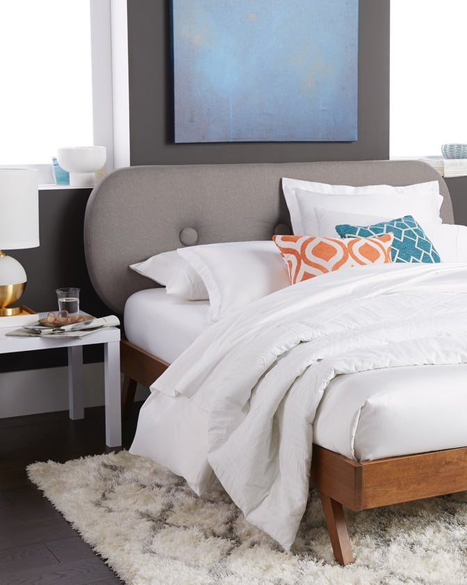 A mid-century modern bedroom with a modern bed frame and mid-century style bedding. Starts off a blog post about how to style with mid-century modern designs.