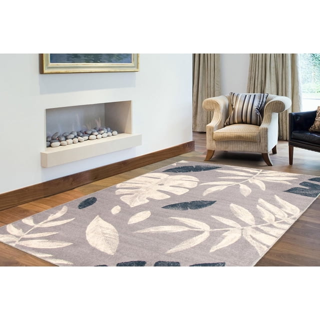 Floral area rug from ECARPET Presly Collection featuring large white and dark blue leaves on light gray, placed in a modern living room with armchairs and fireplace.
