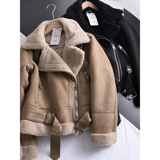 chaqueta corta de piel de oveja para mujer, abrigo grueso y cálido de ante color negro; vista 3/4 frontal con forro sherpa a la vista, cierre de cremallera asimétrico, solapa con cuello liso forrado, cremalleras en bolsillos, fajas con hebilla en la cintura y puños con borrego expuesto, estilo streetwear para otoño/invierno, también suele usarse como abrigo de fin de semana para viajes cortos.
