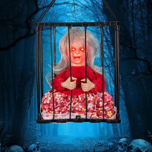 xihbxyly decoración de jaula de calavera para halloween, prisionero gritador activado por movimiento, ojos rojos luminosos: vista frontal centrada de una muñeca prisionera en una jaula negra de barras verticales con vestido rojo y falda floral multicolor, cabello gris y manos agarrando las barras; fondo de bosque nocturno azul. Ideal para decoración temática de casa embrujada y fiestas; suele usarse para ambientar mesas o entradas; funciona con pilas.