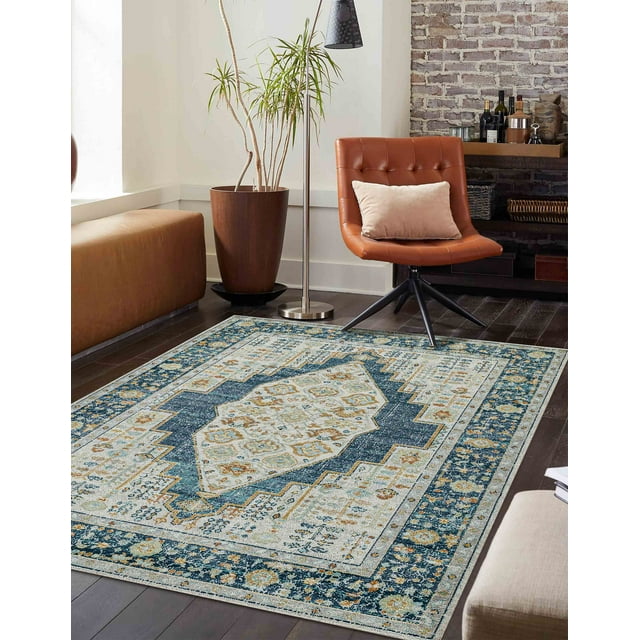 ECARPET Kinsley traditional area rug featuring blue, beige, and gold geometric designs placed on dark hardwood floor in a contemporary living room with leather chair and potted plant.