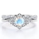 thumbnail image 1 of JeenMata Anillo de Bodas con Banda Trenzada Infinita de Moissanita y Piedra Lunar Azul de Talla Redonda de 1,75 Quilates con Bisel de Halo de Flores Engastado en Oro Blanco de 18 K sobre Plata, 1 of 6