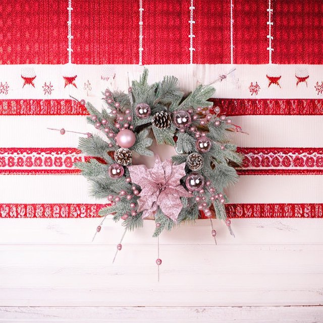 corona navideña rosa para puerta con bolas, ventana, corona rosa para decoración del hogar de año nuevo guirnalda importada en rosa con piñas de ratán, agujas de pino artificiales, bolas decorativas y flor poinsettia central; vista frontal centrada sobre pared a rayas, para puerta, ventana o sala; uso interior o exterior y adecuada como regalo festivo.