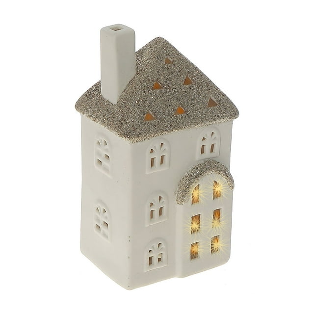 White ceramic decorative house with glitter-covered roof and warm LED lights shining through arched windows.