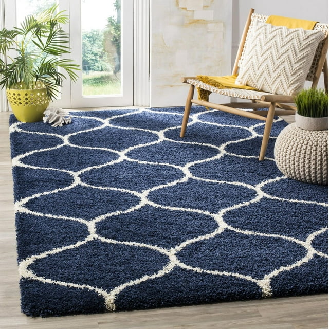 Safavieh Hudson Arline blue shag area rug featuring a white geometric trellis pattern, styled in a sunlit room with modern wooden chair and greenery.
