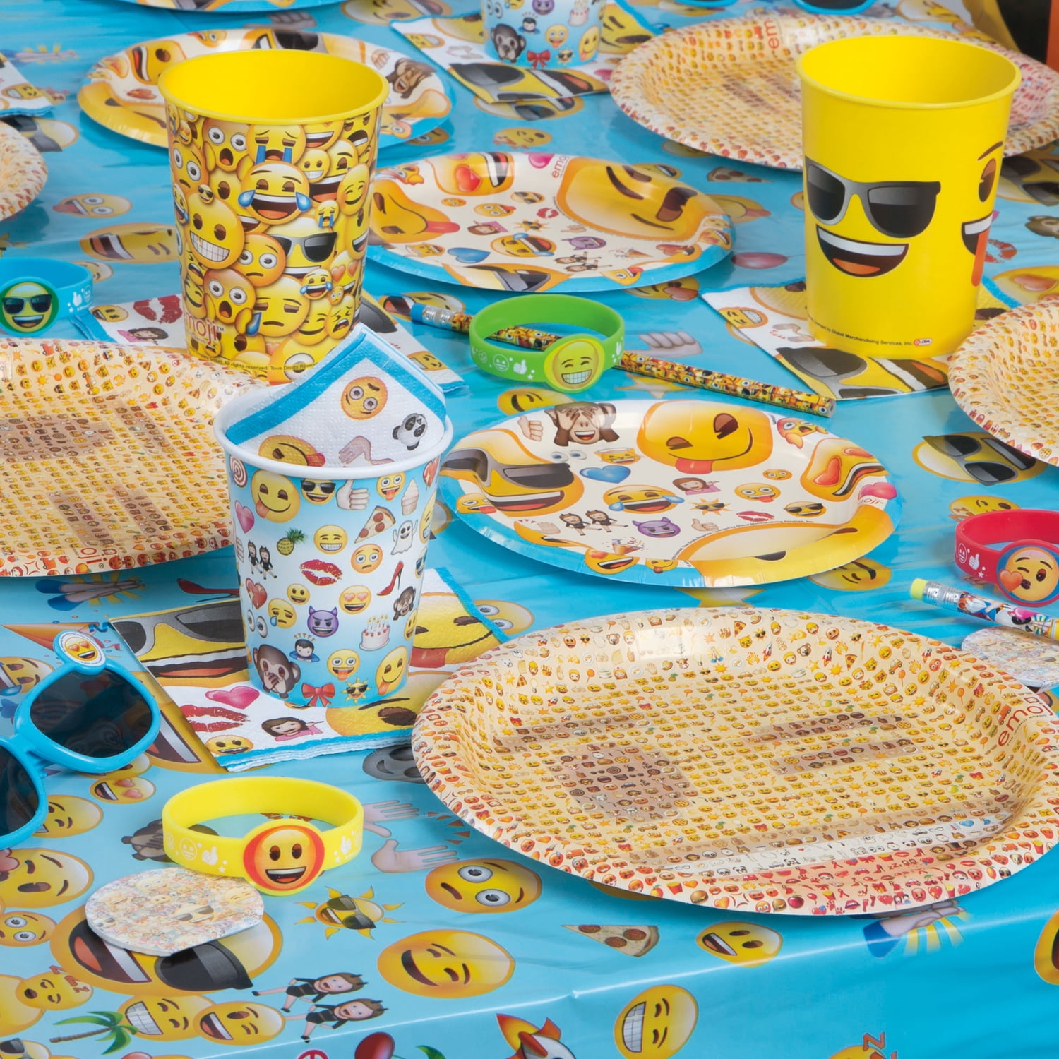 Set a fun, retro emoji party table with an All Smiles Smiley Face Birthday  Party Supply Kit for 16 Guests. The kit has a table cover, 2 sizes of  plates, and napkins