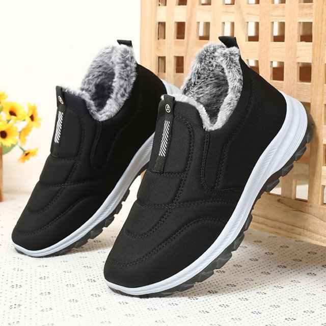 botas de nieve para hombre, botines térmicos ligeros con forro de piel sintética gris, par negro en vista 3/4 frontal con suela blanca y banda de tracción negra, corte de Lycra algodón y costuras acolchadas con ajuste sin cordones, ideales para viajes y senderismo; también suelen usarse como calzado casual abrigado para caminatas urbanas.