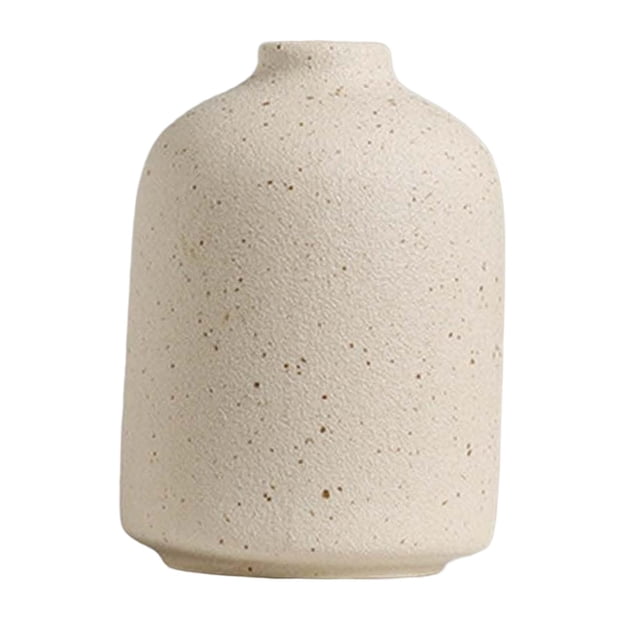 florero de cerámica arreglos florales floreros decorativos para cocina dormitorio cena 10cmx7cm jarrón beige Zulema, vista frontal centrada de un florero de mesa de cerámica con silueta cilíndrica corta y cuello pequeño, acabado texturizado beige con motas oscuras, ideal para arreglos florales y decoración de cocina, dormitorio o escritorio; medida 10 cm x 7 cm. También suele usarse como adorno minimalista independiente en estantes o tocadores.