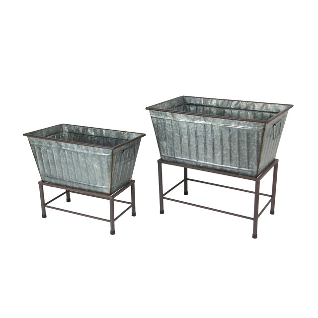 Set of 2 galvanized grey zinc finish metal tub planters on stands, featuring a rustic design with ribbed detailing and elevated on sturdy metal legs. The larger planter measures 20 inches long, while the smaller one is 17 inches long. Ideal for garden decor, these planters can also be used as decorative storage or party tubs for beverages.