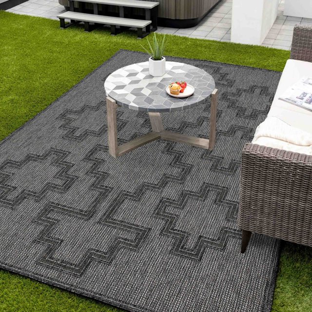 ECARPET Esina transitional gray area rug with textured geometric crosses pattern displayed outdoors under a mosaic round coffee table next to wicker seating