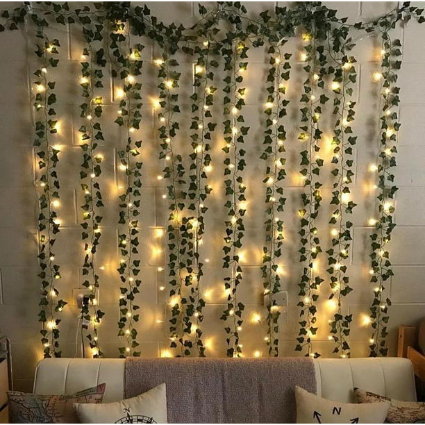 Several vines of green leaves fairy lights are hung on the wall