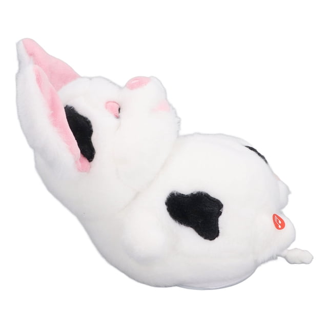 juguete de cerdo parlante de felpa suave con orejas móviles, desarrollo de habilidades lingüísticas para bebés peluche interactivo blanco con manchas negras, vista lateral 3/4 acostado que muestra orejas interiores rosadas y botón naranja visible, textura de felpa suave y silueta redondeada, a menudo usado como compañero de juego para bebés.