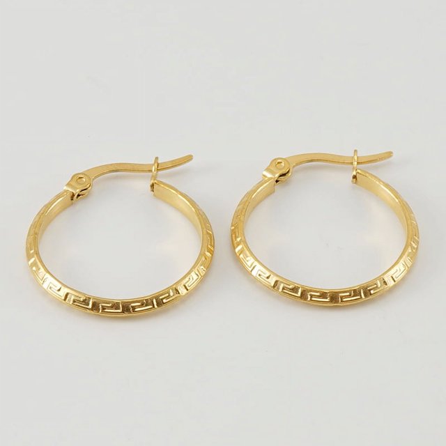 pendientes de hebilla con patrón de gran muralla de acero de titanio dorado de 18 k, aros de 23 mm en tono dorado con cierre de hebilla visible y patrón geométrico grabado en el borde, vista cenital sobre fondo neutro; aptos como aros diarios o para combinar en conjuntos formales.