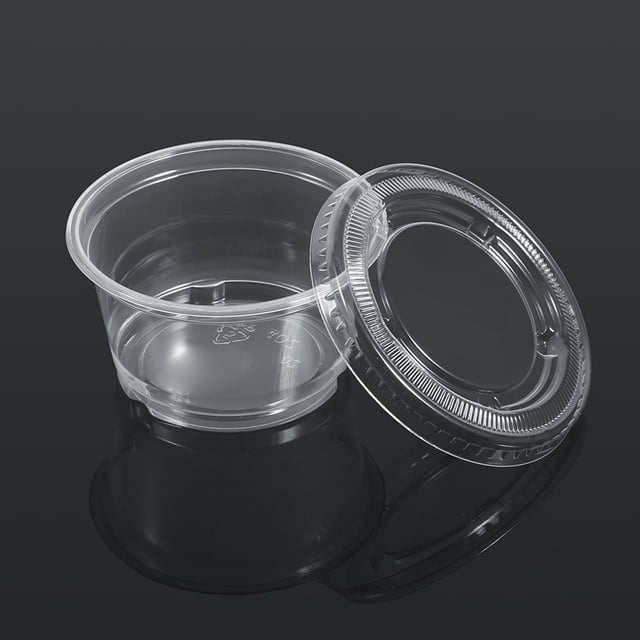 vaso para salsa picante, 50 unidades vaso desechable de plástico transparente para salsa vaso plástico para chutney de alta capacidad Vista frontal centrada de un vaso de PP transparente (ej. tamaño 2 oz) con la tapa retirada y apoyada al lado; cuerpo cilíndrico bajo con borde enrollado, base plana con marcas moldeadas y tapa encajable con pestañas para sello; sobre fondo oscuro reflectante, indicado para condimentos, aderezos y servicio para llevar, ideal para restaurantes y eventos.