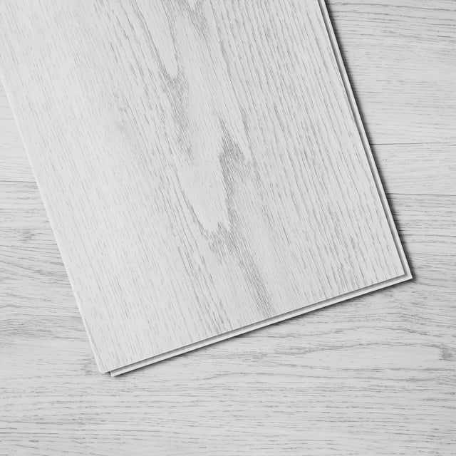 vevor baldosas de vinilo entrelazadas de 48 x 7,3 pulgadas, 10 baldosas de 5,5 mm de grosor que se unen, pisos de bricolaje de grano de madera gris claro para cocina, comedor, dormitorios y baños Primer plano de una loseta VEVOR colocada en diagonal sobre fondo de tablas del mismo tono; loseta rectangular con patrón de veta de madera gris claro, canto click-lock visible y superficie lisa texturizada que imita madera. Ideal para instalación DIY en cocinas, baños y oficinas; suele usarse también para renovar comedores y dormitorios.