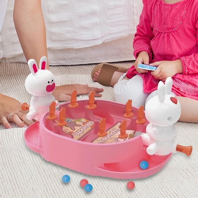juego de pinball de escritorio, juguetes de coordinación mano-ojo, juego de mesa de interacción para niños de 3 años o más, regalo de cumpleaños, rosa — tablero rosa de 21 cm x 11 cm visto en plano medio con dos figuras de conejo blancas como lanzadores, ocho clavijas naranjas en la superficie y pelotitas azules y rosas; diseñado para partidas de 2 jugadores para entrenar precisión y velocidad de reacción; a menudo se usa como juguete de mesa para fiestas familiares.