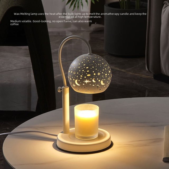 lámpara de cera derretida lámpara de aromaterapia lámpara de cielo estrellado lámpara de vela derretida lámpara de cera ardiente lámpara de noche lámpara de mesa ENTASSER, vista frontal 3/4: lámpara de mesa compacta con pantalla esférica perforada con motivos de luna y estrellas, brazo curvado metálico y base redonda con plato para vela o difusor; luz cálida y difusa que crea un ambiente relajante y es adecuada también para usar como difusor de aceites esenciales en habitaciones pequeñas.