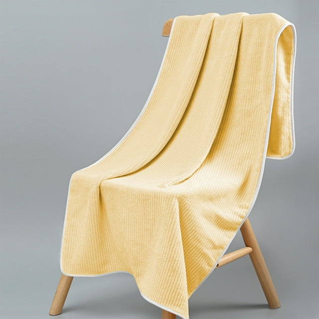 luxury bath towels - all cotton-ultra soft- plush- thick-- absorbent- quick dry- home- gym- pool- yoga- hotel- shower- large towel for bathroom deals of the day clearance Yellow coral fleece bath towel 34×76cm (13.4×29.9 in), front-facing drape over a wooden stool showing ribbed plush texture and white piped edge; studio gray background, for home, gym or hotel use and often suitable as a yoga or travel wrap.