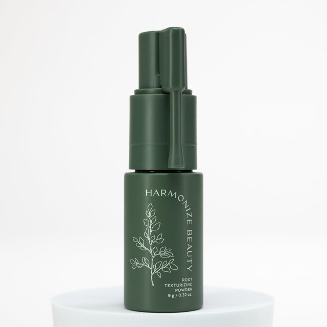 root texture powder harmonize beauty para mujeres Verde frasco — frasco verde mate frontal del polvo de textura para raíces Harmonize Beauty con aplicador de boquilla y tapa, etiqueta blanca con ilustración botánica y texto vertical; colocado sobre base blanca con fondo neutro. Diseñado para aportar volumen y elevación instantánea en raíces, ideal para retoques rápidos y uso en viaje.