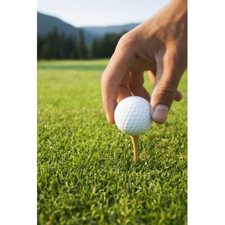 Golfer sets up a ball on the tee of a golf course on a summer evening Whistler British Columbia Canada