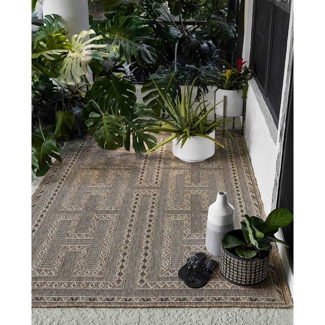 ECARPET Hazel transitional area rug featuring a beige and brown geometric design on a porch floor, styled with green potted plants and black sandals.