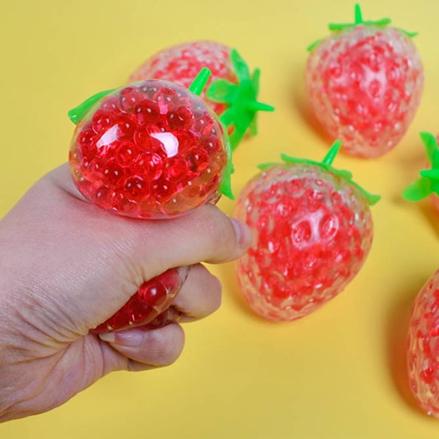 Pelota antiestrés con forma de fresa simulada que se puede apretar y soltar para liberarla.
