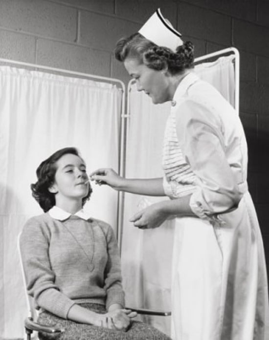 Female nurse taking the temperature of a girl with a thermometer Poster