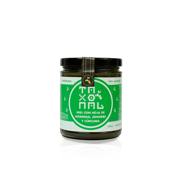 taxonal, miel con hoja de moringa jengibre y curcuma, 100% pura, 320gr. Frasco de vidrio centrado, vista frontal con tapa negra y etiqueta verde que muestra el logotipo Taxonal y el texto "miel con hoja de moringa, jengibre y cúrcuma"; peso indicado 320 g, fondo blanco.