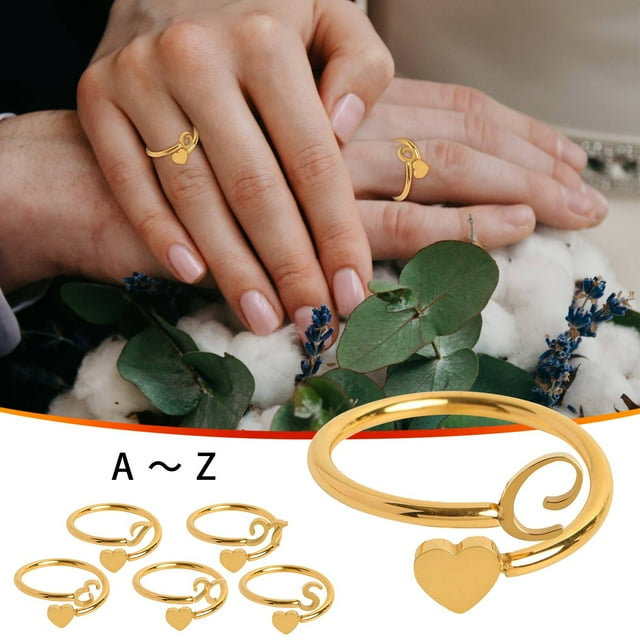 onlyliua para interior/exterior anillos y letras iniciales en oro y mujeres y niñas — Anillos dorados apilables en vista detallada; anillo abierto en espiral con colgante en forma de corazón y mini letras A–Z, manos femeninas luciendo anillos sobre ramo con eucalipto y algodón, diseño apilable adecuado como regalo para mamá, esposa o novia.