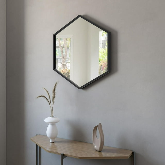 A&E Bath and Shower DELTA-BM hexagonal mirror with black frame hanging on gray wall above wooden console table holding two modern vases.