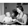 Mother feeding baby boy in high chair Poster Print