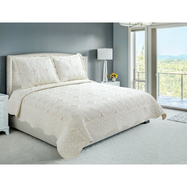 Cream embroidered stitching coverlet bedspread and quilted shams featuring geometric circles pattern on a neatly made bed in bright bedroom.