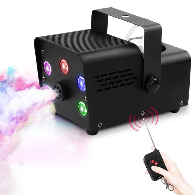 máquina de humo stageglow con 5 luces led rgb y control remoto Máquina de humo negra 550W con cinco LED RGB frontales, chasis metálico y carcasa plástica, vista 3/4 frontal con boquilla expulsando niebla blanca pura, soporte superior abatible y control remoto inalámbrico visible; ideal para fiestas, DJ y escenarios y a menudo usada también para ensayos teatrales.
