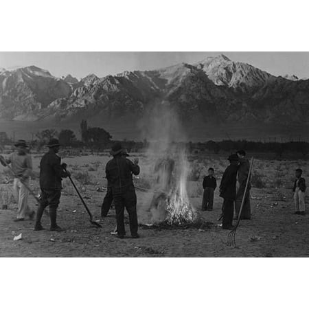 men and boys standing around a small brush fire holding shovels a pitchfork stands in the right foreground mountains in background  Ansel Easton Adams was an American photographer best known for his