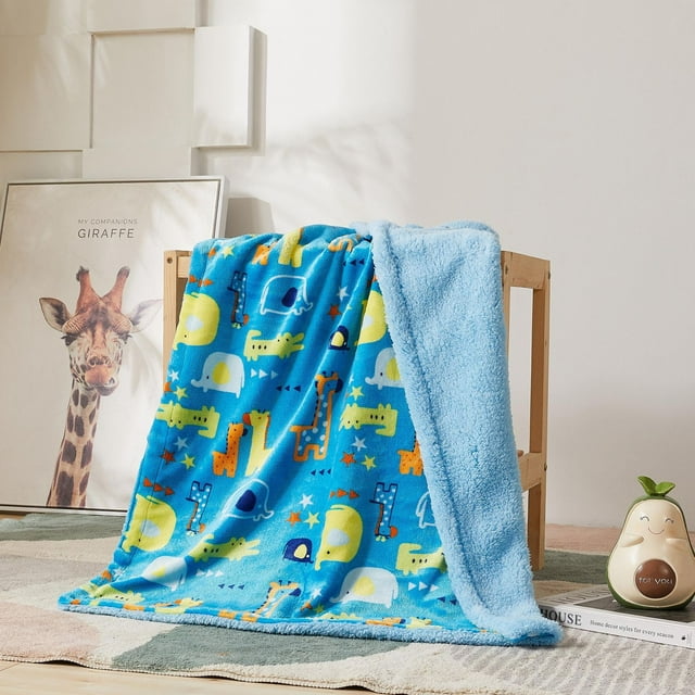 Reversible blue kids blanket with colorful animal zoo prints like giraffes, elephants, and crocodiles on one side and soft fluffy sherpa fleece on the other side draped over a wooden chair in a cozy room setting