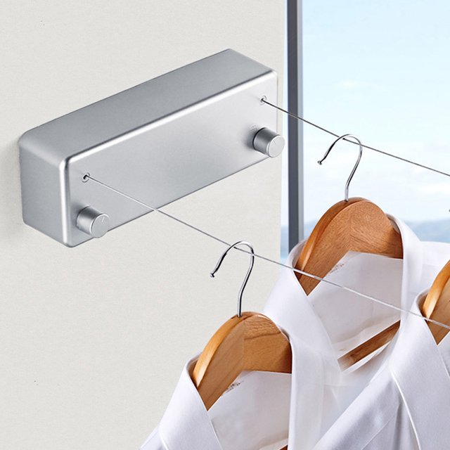 tendedero retráctil, líneas duales tendedero retráctil tendedero línea de secado de ropa elegante y moderno — tendedero de pared VoborMX en plata, vista 3/4 con carcasa rectangular y dos cables extensibles plateados que salen de pomos circulares; sostiene perchas de madera con camisas blancas. Instalación por perforación; materiales ABS, aluminio y acero inoxidable; cable aprox. 4 m; carga máxima 15 kg. También suele usarse para secar prendas pequeñas en espacios reducidos.